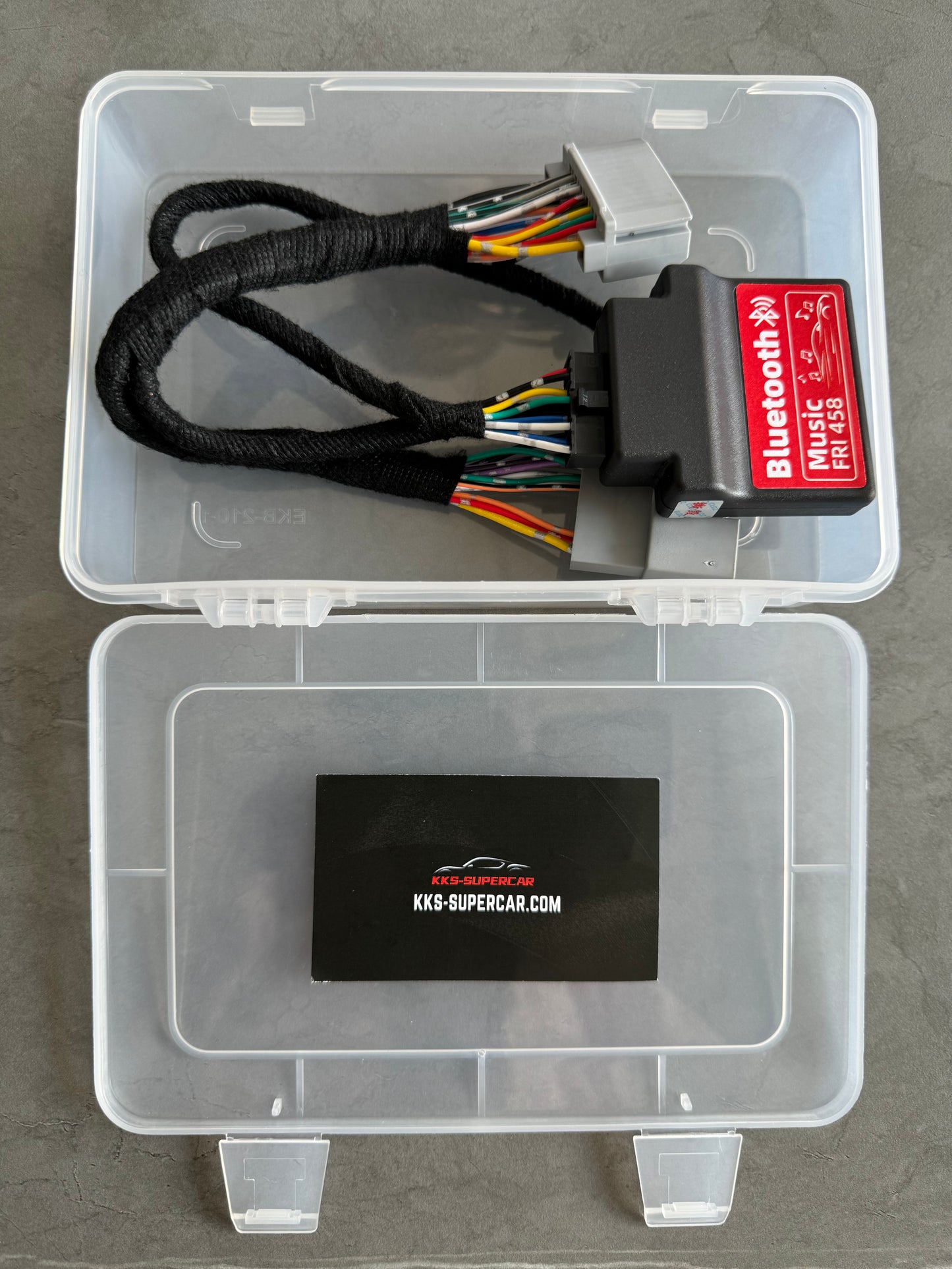 Bluetooth music interface module with wiring harness for exotic car, displayed in clear box