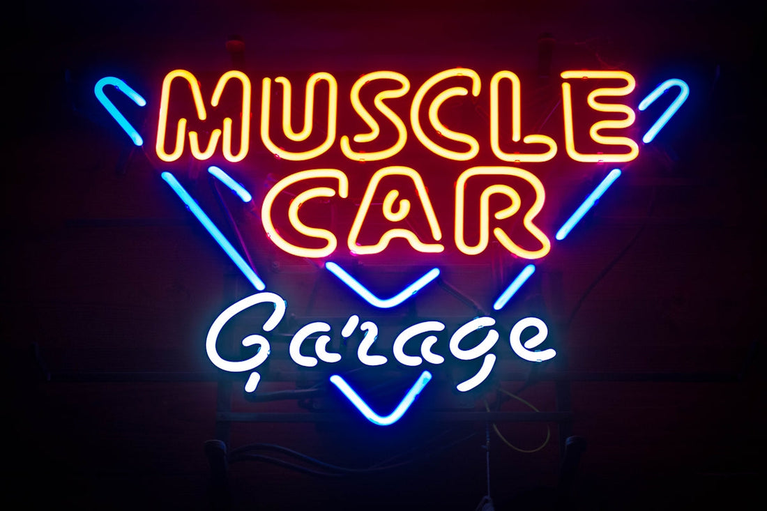 Neon sign reading Muscle Car Garage with vibrant red, yellow, and blue lights