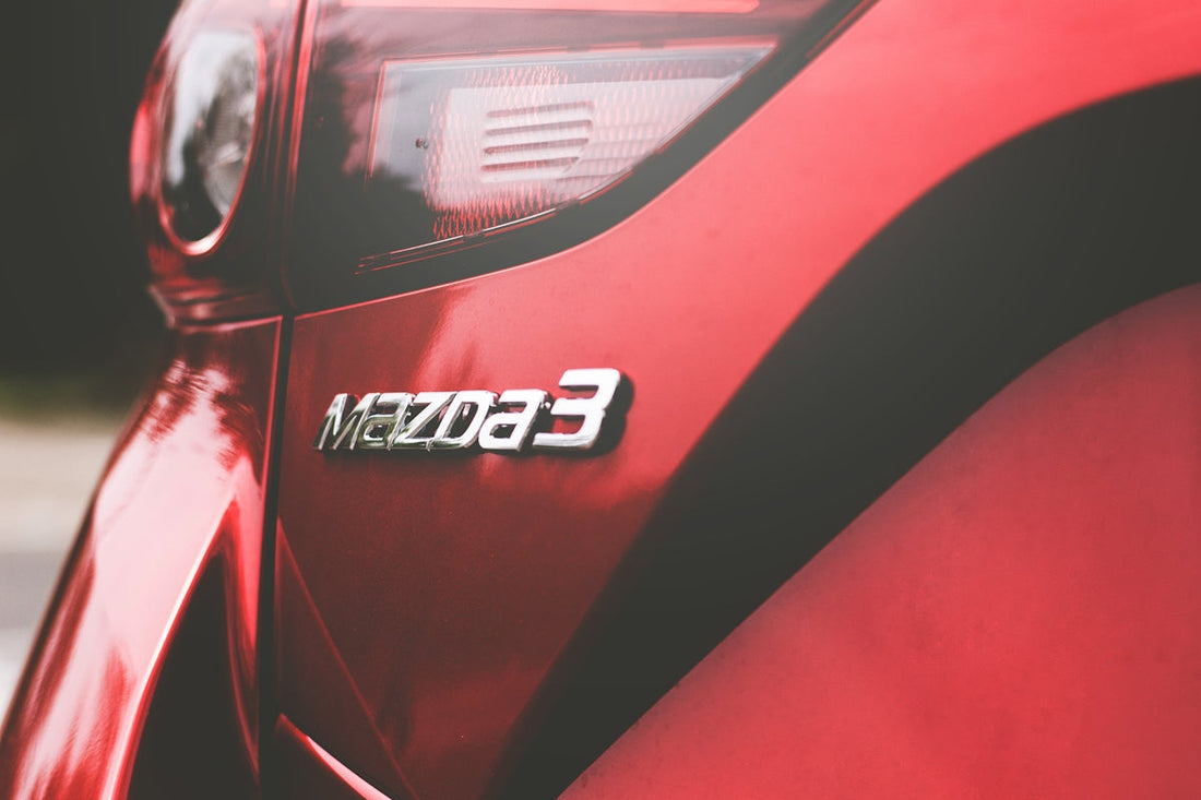 Close-up of red Mazda3 rear badge and taillight, modern compact car detail