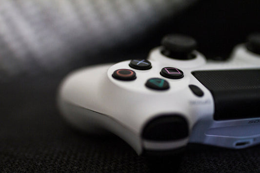 Close-up of a white video game controller with focus on buttons, resting on a dark fabric.