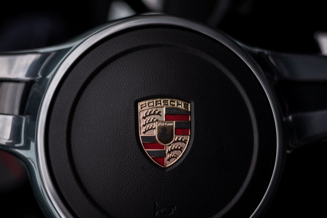 Close-up of Porsche steering wheel with emblem, luxury car interior detail