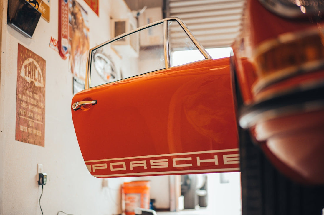 Orange Porsche classic car door open in a vintage garage setting