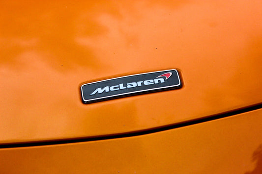Close-up of McLaren badge on orange exotic supercar hood