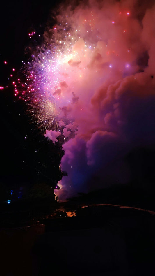 Colorful fireworks exploding in the night sky with vibrant smoke and bright sparks