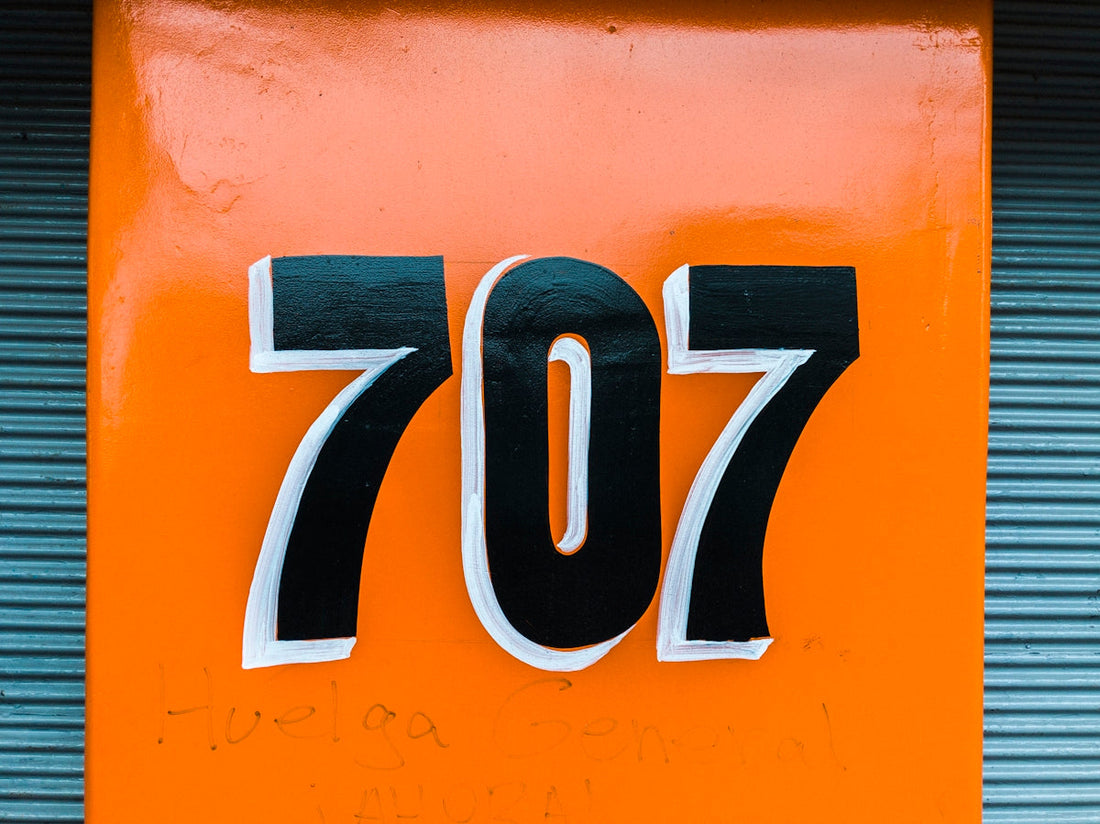Black and white number 707 on an orange background, metallic ridged surface beside