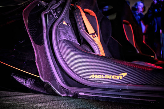 Close-up of McLaren carbon fiber door sill and orange-accented sport seats