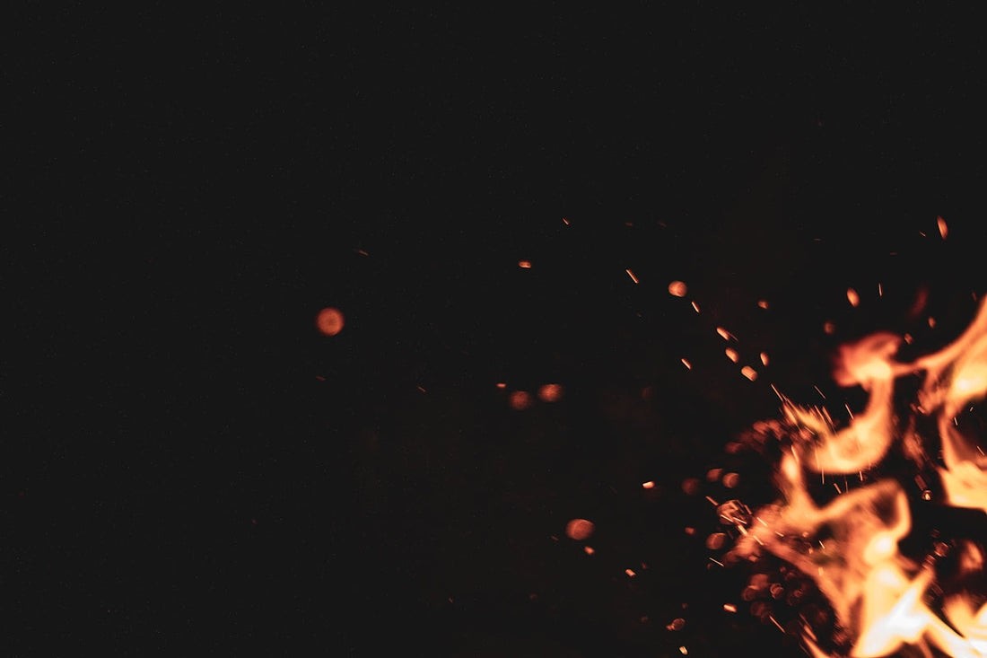 Close-up of orange fire flames and sparks against a dark black background