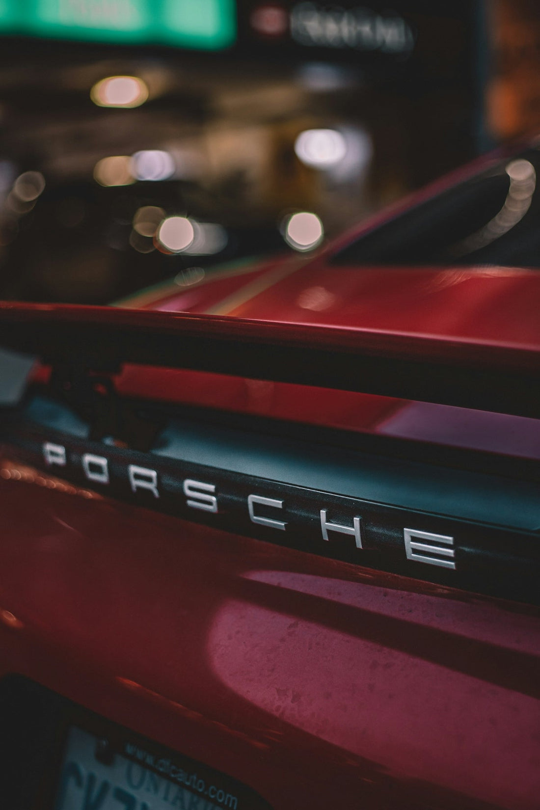 Close-up of red Porsche sports car rear with spoiler, emphasizing luxury supercar design.