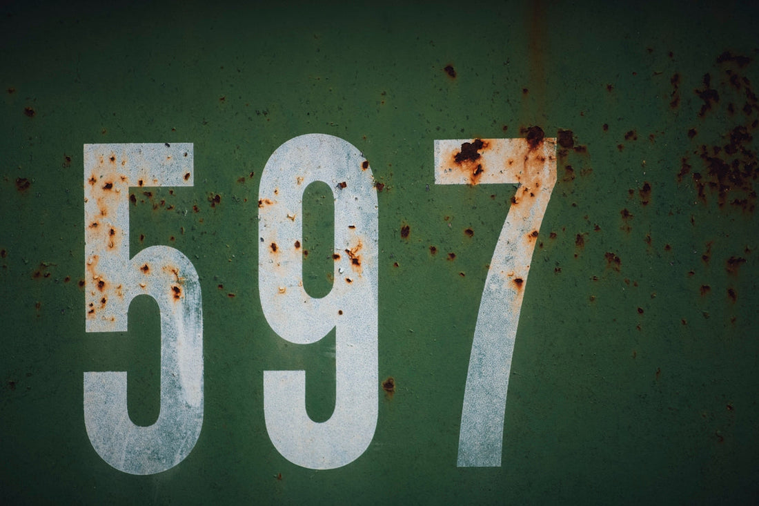 Large white numbers 597 on a green, weathered metal surface with rust spots