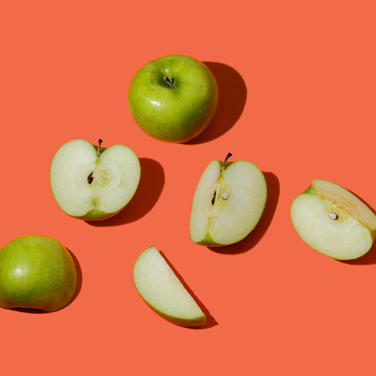 Green apples whole and sliced on bright orange background