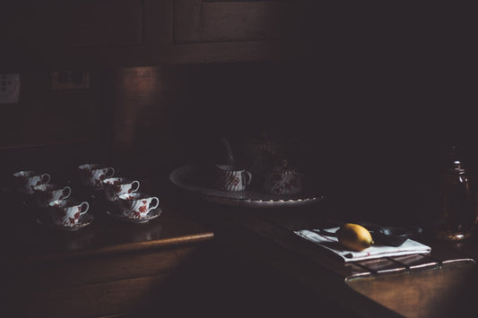 Vintage tea set and lemon on dark wooden kitchen counter, soft moody lighting