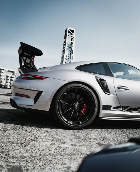 white and black porsche 911 parked on gray concrete pavement during daytime