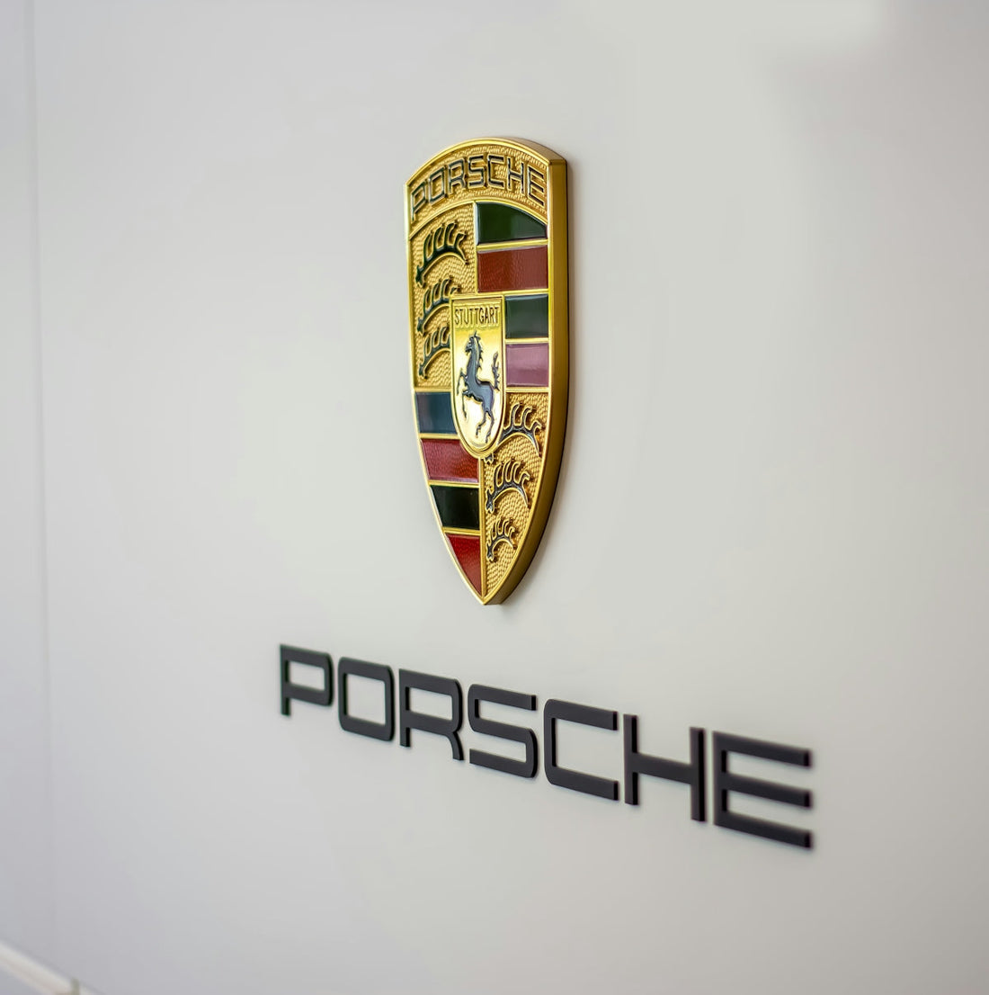 Porsche crest and logo on a sleek wall, luxury car brand emblem detail