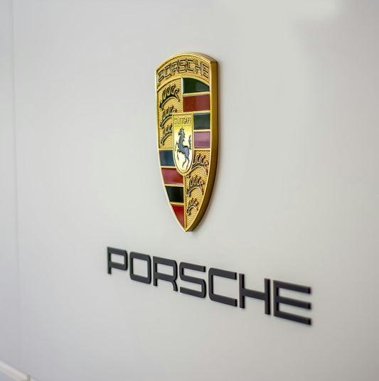 Porsche crest and logo on a sleek wall, luxury car brand emblem detail