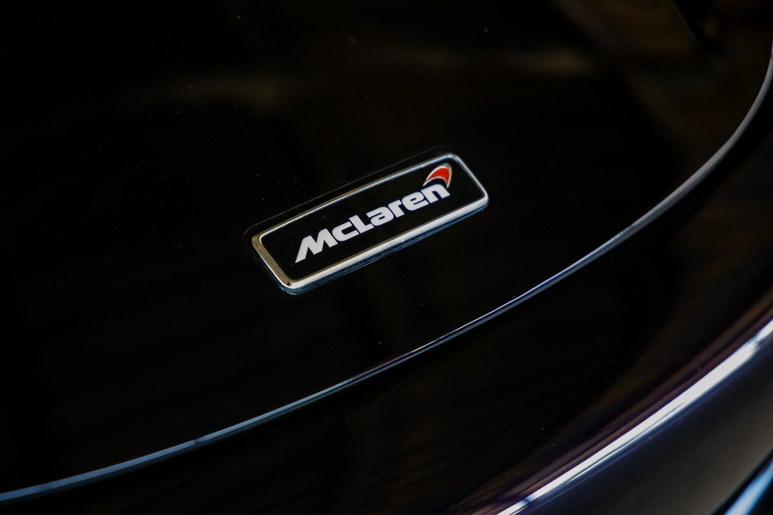 Close-up of McLaren car badge on glossy black hood, exotic supercar emblem