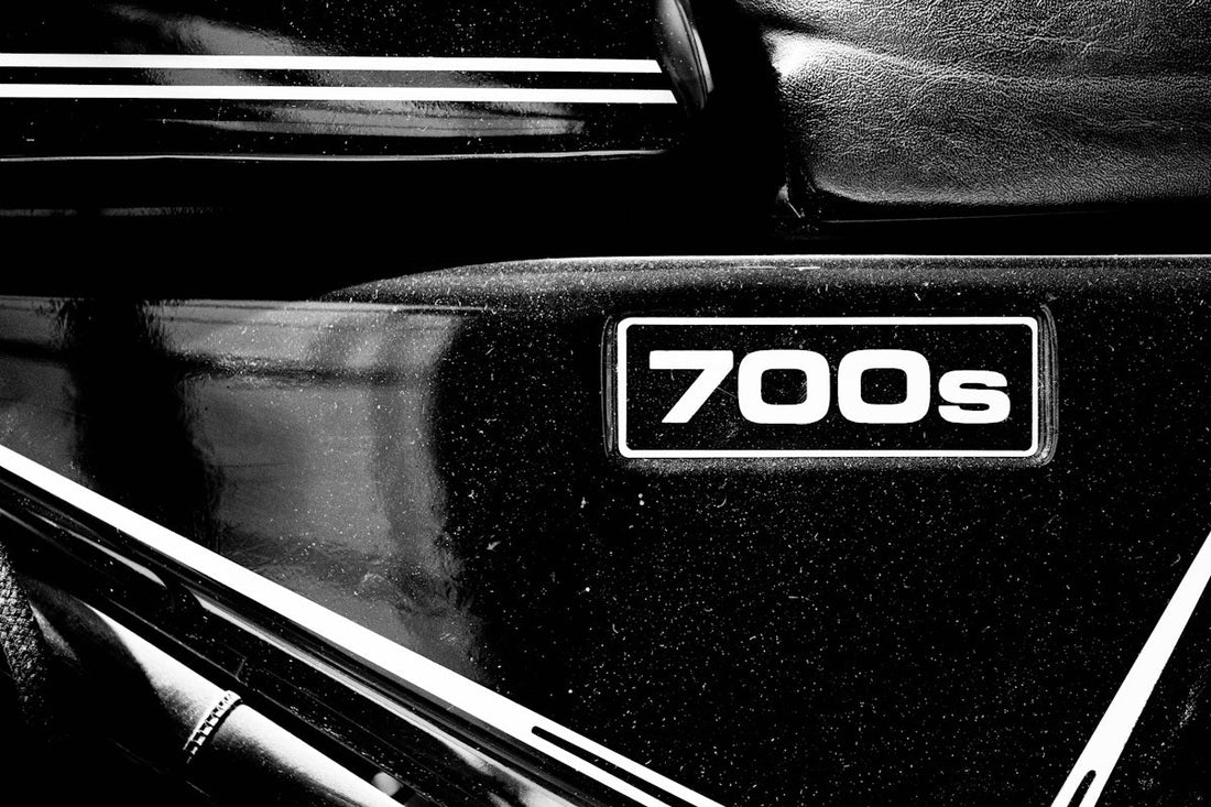 Close-up of 700s badge on black supercar body with white racing stripes