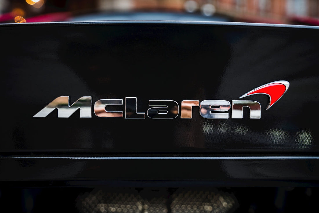 Close-up of McLaren logo badge on a black exotic sports car