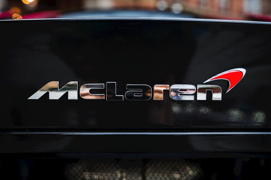 McLaren supercar rear badge close-up, chrome logo on black exterior