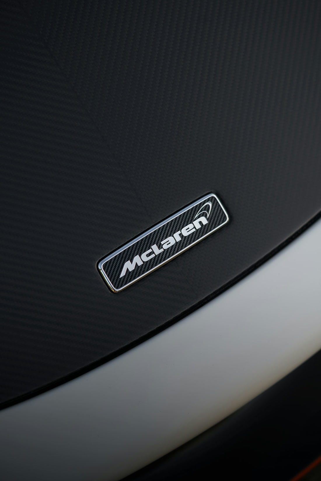 McLaren emblem on carbon fiber supercar hood, luxury exotic car detail