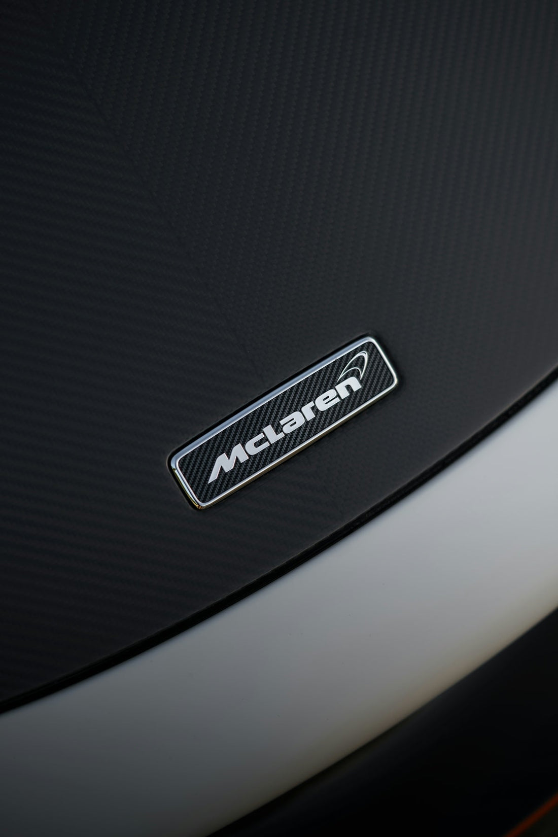 Close-up of McLaren badge on carbon fiber supercar hood
