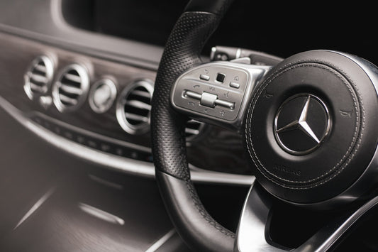 Luxury car interior with black leather Mercedes-Benz steering wheel and dashboard controls