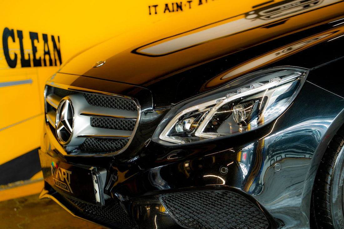 Close-up of black Mercedes-Benz front grille and headlight, luxury car detail