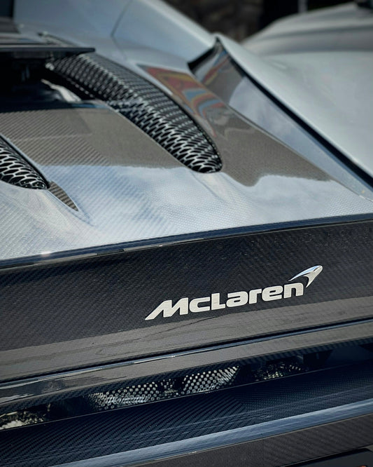 Close-up of McLaren car carbon fiber engine cover and logo, luxury exotic sports car
