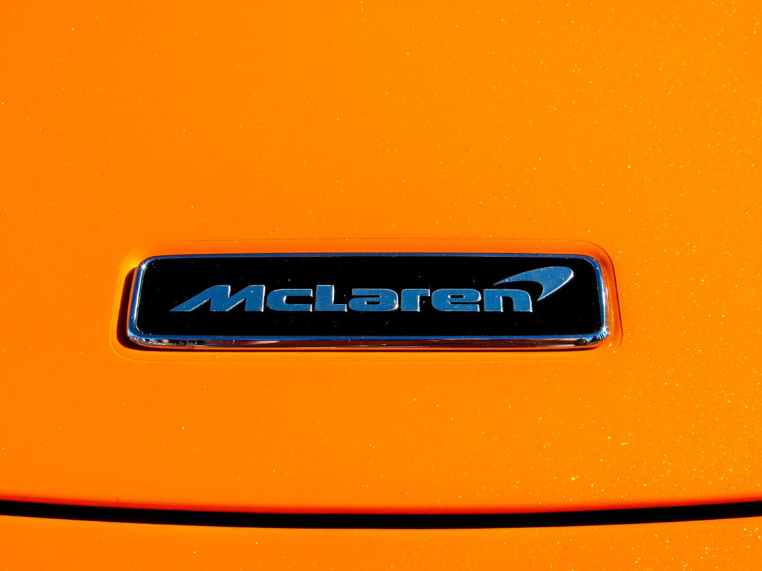 McLaren car badge on bright orange hood, luxury supercar detail
