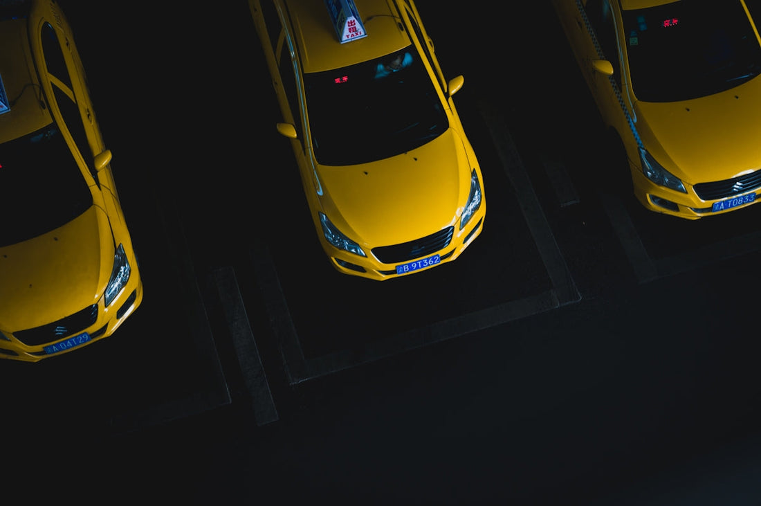 Overhead view of three yellow taxis parked in a dark parking lot