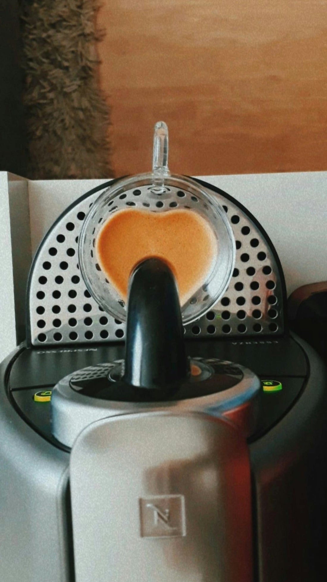 Espresso machine brewing coffee with heart-shaped crema in glass cup