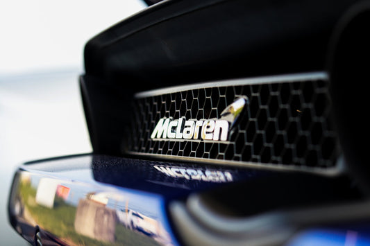 Close-up of McLaren emblem on rear grille of a blue sports car