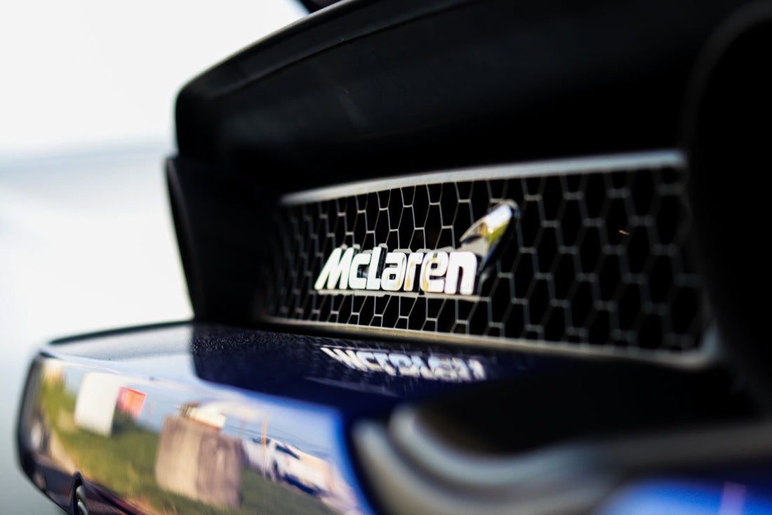 Close-up of McLaren logo on car grille, luxury supercar detail, honeycomb mesh background
