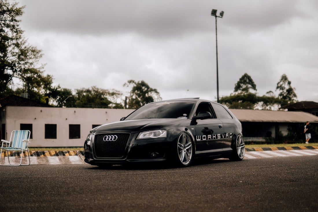 Sleek black Audi hatchback with custom wheels parked outdoors on overcast day
