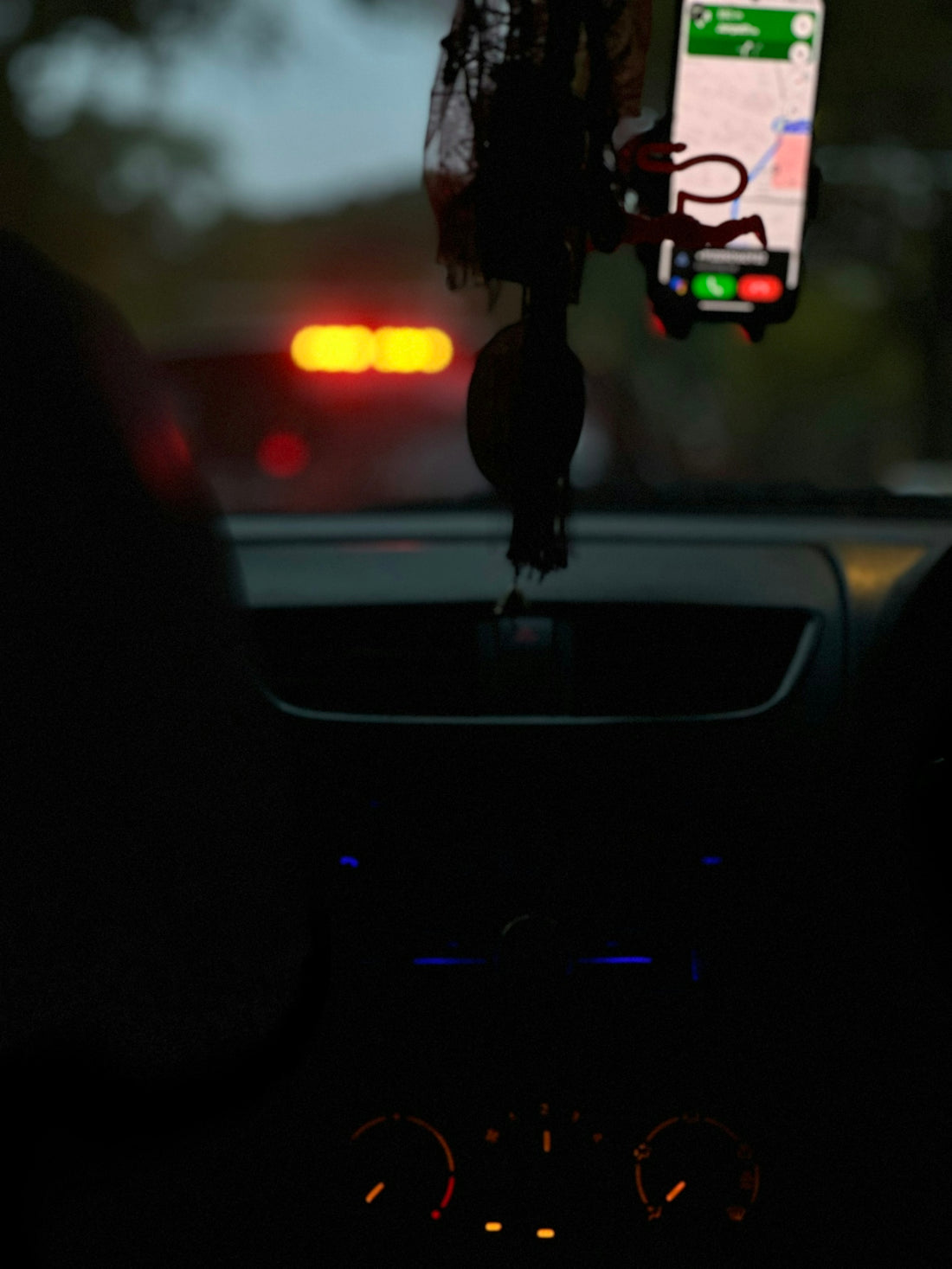 a car dashboard with a cell phone hanging from the dash