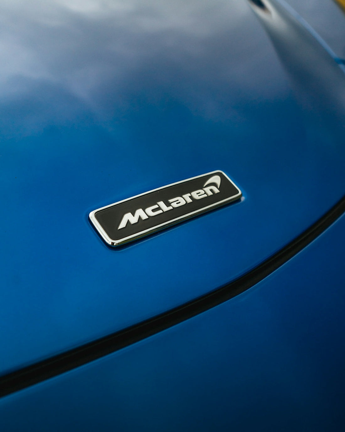 McLaren badge on blue supercar hood, luxury exotic car detail