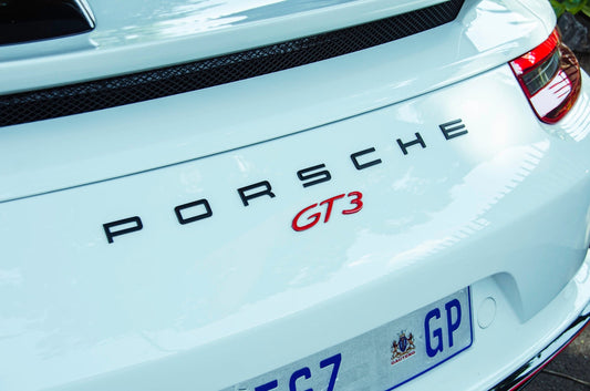 Close-up of white Porsche GT3 rear badge and taillight, luxury sports car detail