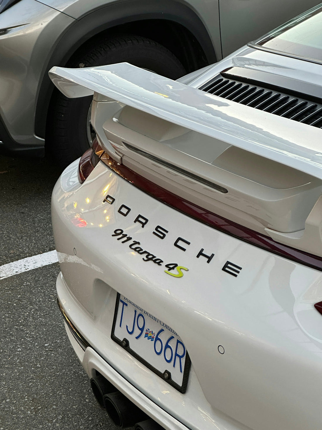 White Porsche 911 Targa 4S rear view with spoiler, parked in a lot, luxury sports car