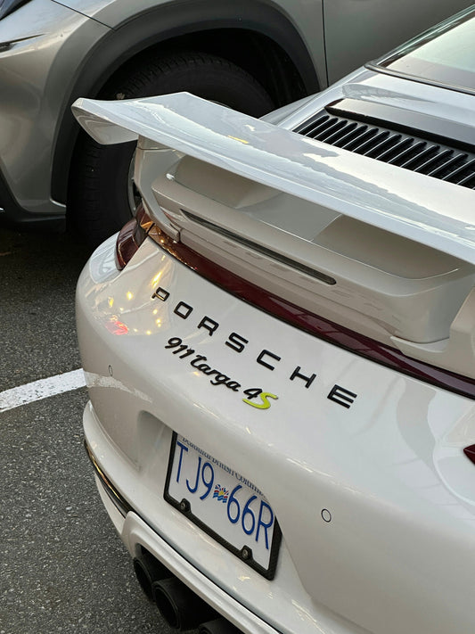 White Porsche 911 Targa 4S rear view with spoiler, parked in a lot, luxury sports car