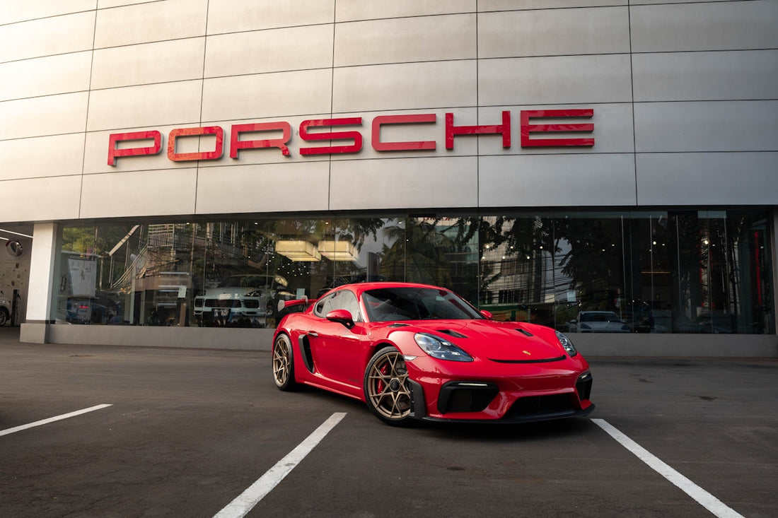 Red Porsche sports car parked outside dealership, sleek exterior and modern showroom backdrop