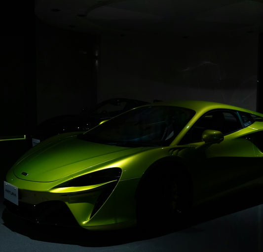 a green sports car parked in a dark room
