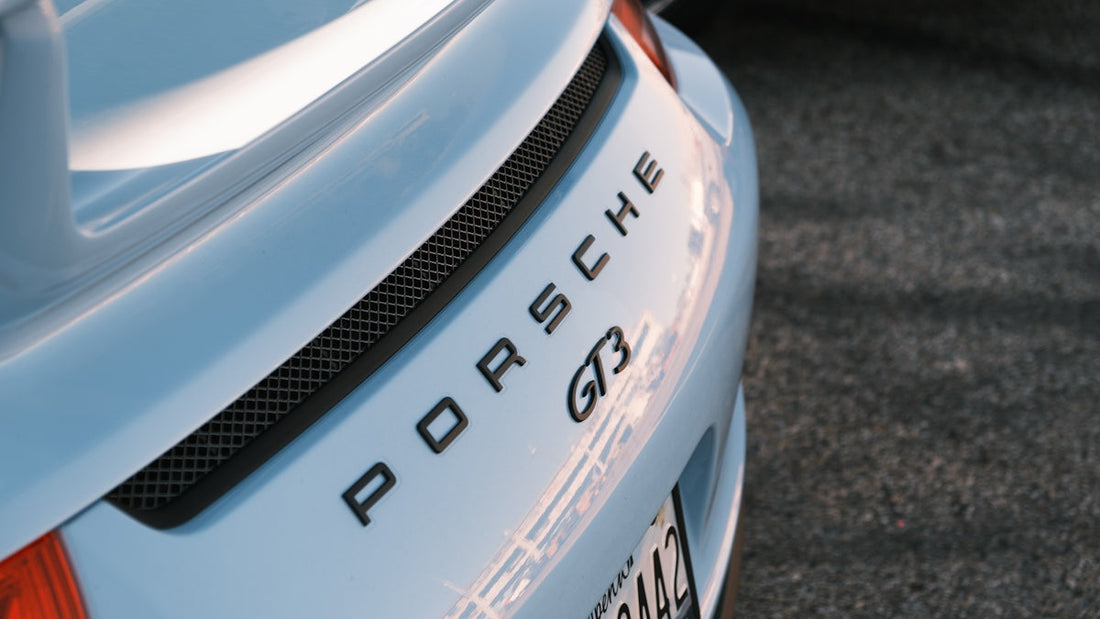 Close-up of silver Porsche GT3 rear trunk badge and spoiler in outdoor setting