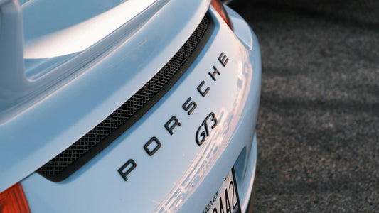 Close-up of silver Porsche GT3 rear trunk badge and spoiler in outdoor setting