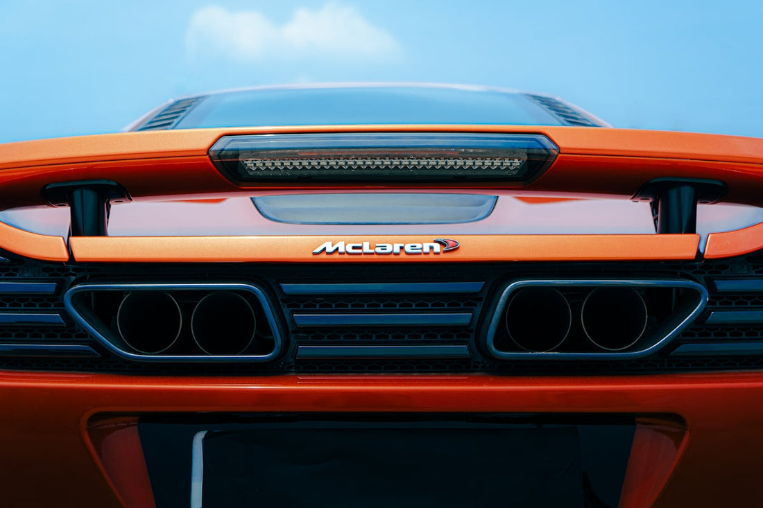 Rear view of orange McLaren supercar with visible exhaust pipes and spoiler