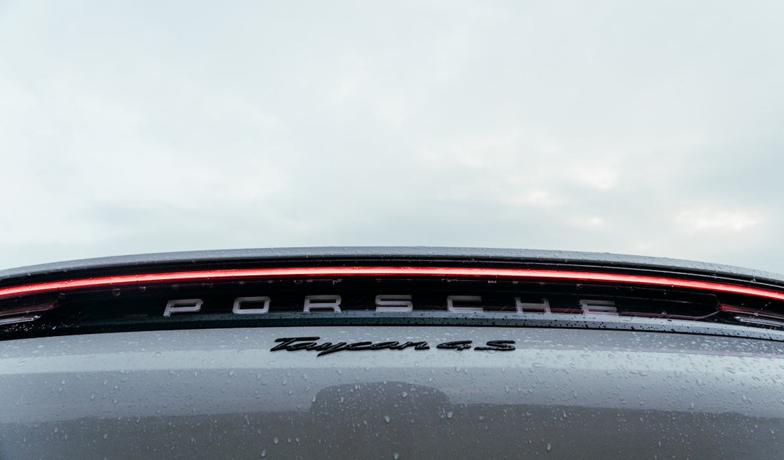 Close-up of Porsche Taycan 4S rear badge and LED tail light with raindrops