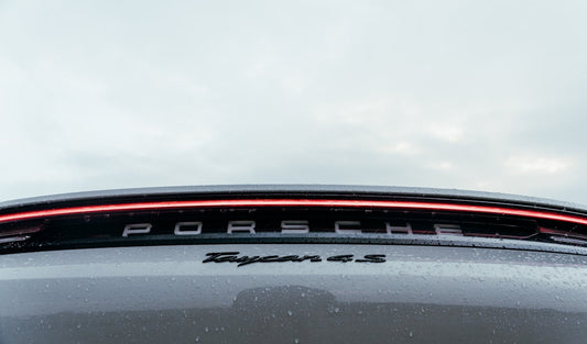 Close-up of Porsche Taycan 4S rear badge and LED tail light with raindrops