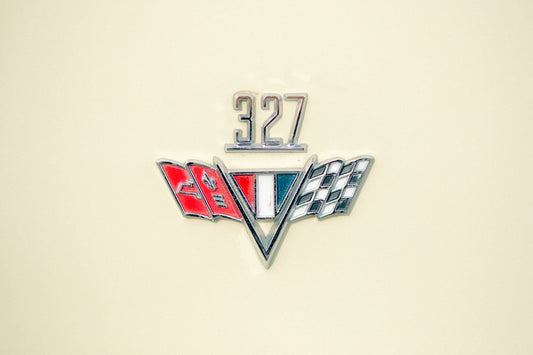 Classic car emblem 327 badge with crossed flags on cream background, vintage automotive detail