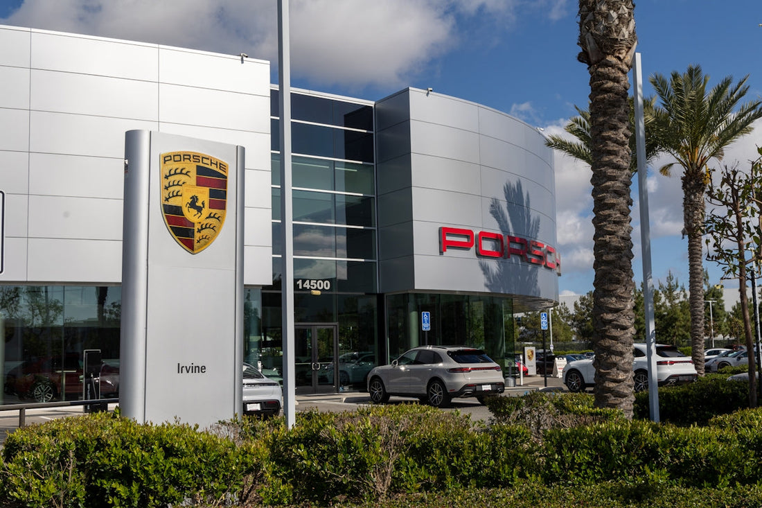 Porsche dealership building exterior with cars parked and palm trees on a sunny day