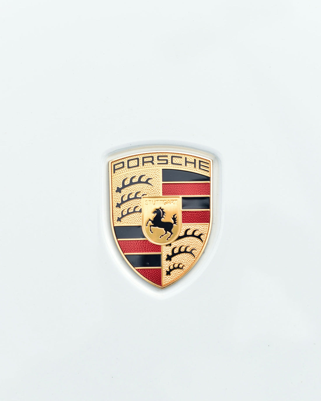 Porsche badge close-up on white exotic car hood, luxury car emblem detail