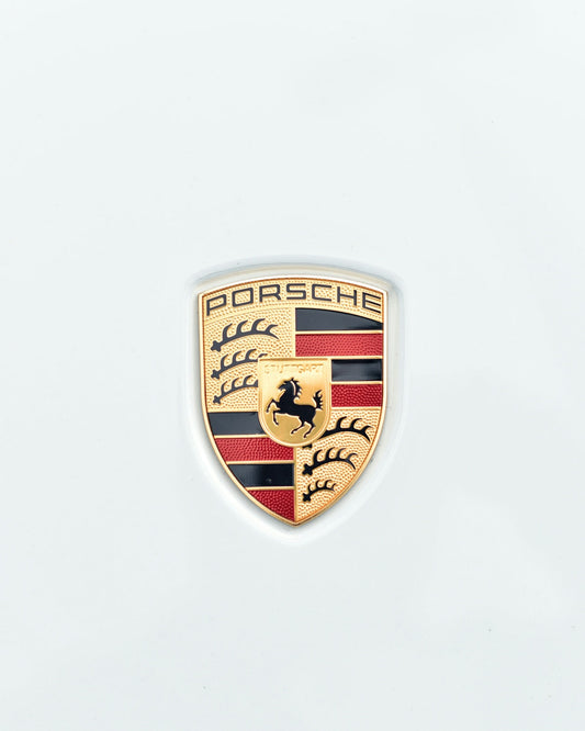 Porsche badge close-up on white exotic car hood, luxury car emblem detail