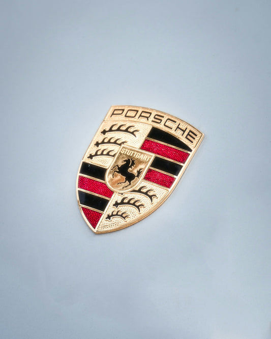 Porsche crest emblem on light gray exotic car hood, luxury car badge detail